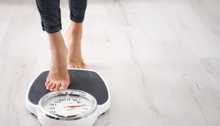 Woman measuring her weight using scales
